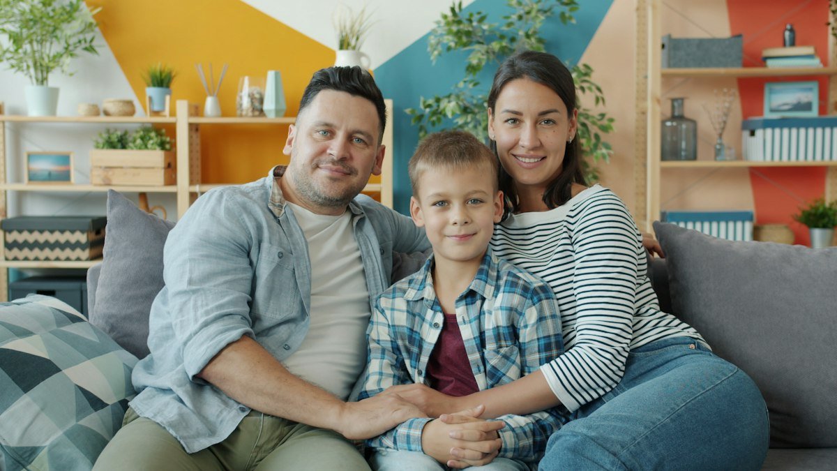Familia sonriente sentada en el sillón de su casa
