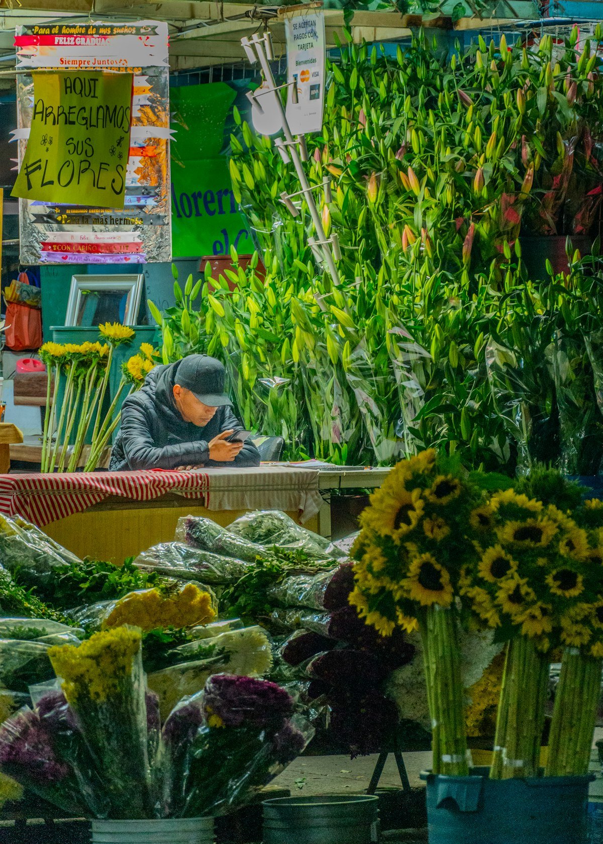 Comerciante de flores revisando su teléfono en su puesto